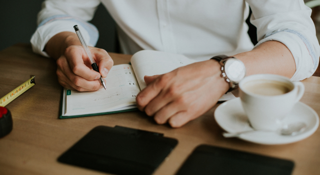 person taking notes notebook while working from home