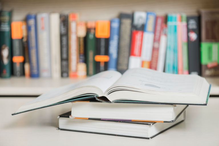 textbooks lying near bookcase